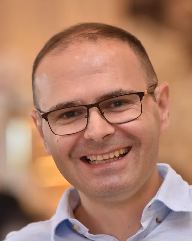 Ivan Đurđevac, smiling, in a light blue shirt and glasses